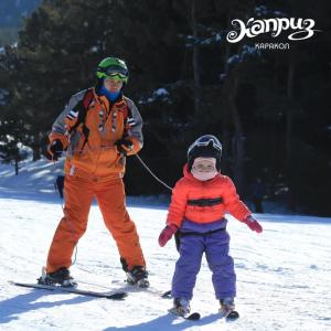 un homme et un enfant à skis dans la neige dans l'établissement Kapriz Karakol, à Karakol