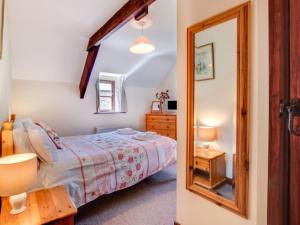 a bedroom with a bed and a mirror at Holiday Home Pusehill Barn-2 by Interhome in Westward Ho
