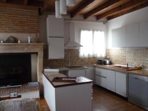 a kitchen with white cabinets and a fireplace at Les Sureaux Le Gite 3 étoiles par CDT24 in Le Pizou