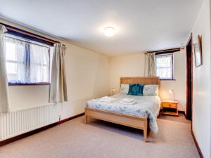 a bedroom with a bed and two windows at Holiday Home Pusehill Barn-2 by Interhome in Westward Ho