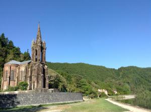 an old building with a clock tower on a hill at Casa Dos Barcos Furnas in Furnas