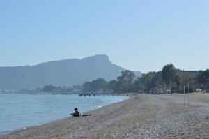 a person sitting on a beach next to the water at Sultan Homes Apartments 2 in Kemer