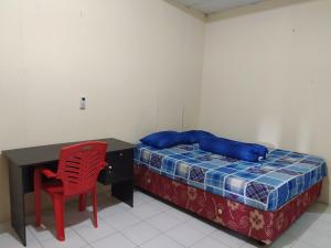 Schlafzimmer mit einem Bett, einem Schreibtisch und einem roten Stuhl in der Unterkunft OYO 3116 Batu Putih Homestay in Makassar