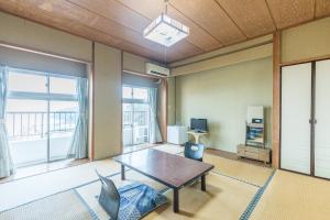 a living room with a table and a large window at Tabist Miyoshi Ryokan Odawara Manazuru in Odawara