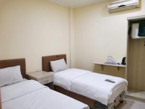 a hotel room with two beds and a table at Hotel Nusantara Indah Syariah in Jakarta