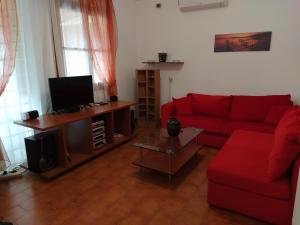 sala de estar con sofá rojo y TV en FAMILY HOUSE NEAR THE BEACH DREPANO-NAFPLIo, en Dhrepanon