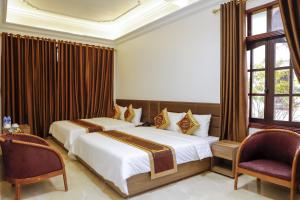 2 Betten in einem Hotelzimmer mit 2 Stühlen in der Unterkunft Vạn Xuân Royal Hotel in Ninh Bình