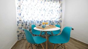 uma sala de jantar com cadeiras azuis e uma mesa e uma janela em Apartamento Realejo 2 Habitaciones em Córdoba