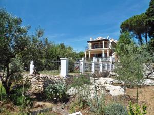 a house on a hill with a fence and trees at Holiday House Klarin with Sea View in Preko