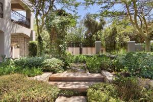 un jardín con un camino de piedra frente a una casa en African Palm Cottage and Guesthouse en Durbanville