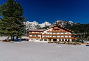 a large building in the snow in front of a mountain at Landhotel Kielhuberhof in Ramsau am Dachstein