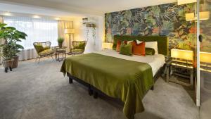 a bedroom with a large bed with a green blanket at Van der Valk Hotel 's-Hertogenbosch – Vught in Den Bosch