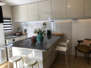 una cucina con armadi bianchi e un bancone con sgabelli di maison de vacances Médiévale Bormes-les-Mimosas village a Bormes-les-Mimosas