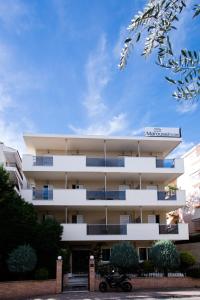 a white apartment building with a motorcycle parked in front of it at Hotel Maroussi in Athens