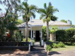 a white house with palm trees in front of it at Carsdale country lodge in Empangeni