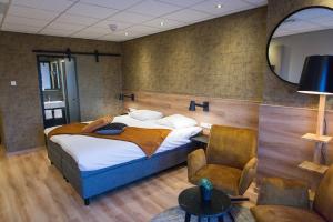 een slaapkamer met een bed, een stoel en een spiegel bij ´t Wapen van Marion in Oostvoorne