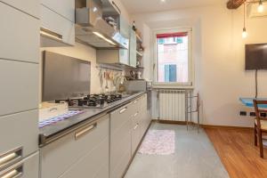 a kitchen with white cabinets and a stove top oven at Realkasa Senzanome Flat in Bologna