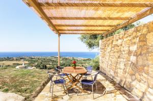 einen Tisch und Stühle auf einer Terrasse mit einer Steinmauer in der Unterkunft Mema's great view Kefalonia in Svoronata