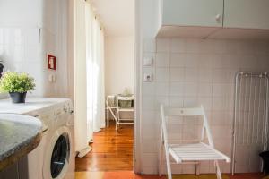 リスボンにあるApartamento Bairro Altoの白い椅子付きのキッチン(洗濯機付)
