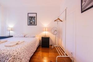 ein weißes Schlafzimmer mit einem Bett und einer Lampe in der Unterkunft Apartamento Bairro Alto in Lissabon