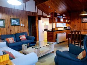 a living room with blue couches and a kitchen at Loch Monzievaird Chalets in Crieff