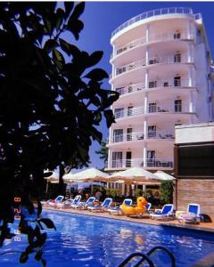 a swimming pool with chairs and a large building at Kobuleti Pearl Of Sea Hotel & Spa in K'obulet'i