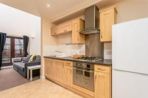 a kitchen with wooden cabinets and a refrigerator at Elliot Suite No 1 - Donnini Apartments in Ayr