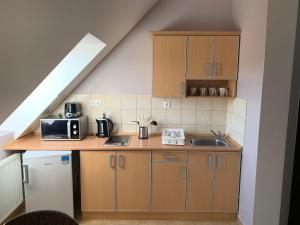 a kitchen with wooden cabinets and a counter with a sink at KarosPool Apartman in Zalakaros