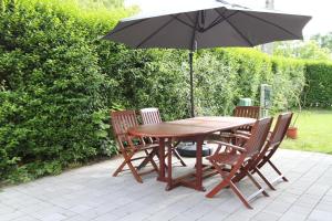 a wooden table and chairs with an umbrella at Velence Lake Apartman in Gárdony