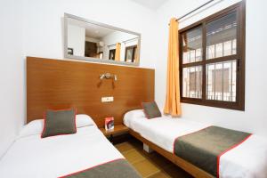 2 camas en una habitación con espejo y ventana en El Rocío Azul Alojamiento Rural, en El Rocío