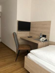 a bedroom with a desk with a television and a bed at Hotel Kögel in Erbach