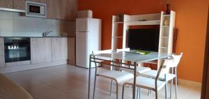 cocina con mesa de cristal y sillas blancas en Apartaments del Llierca, en Sant Jaume de Llierca