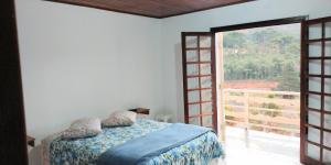 a bedroom with a bed and a large window at Vista Bela in Campos do Jordão