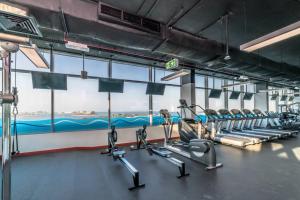 a gym with rows of tread machines and a large window at Holiday Apartment in Palm Jumeirah with Beach Access in Dubai