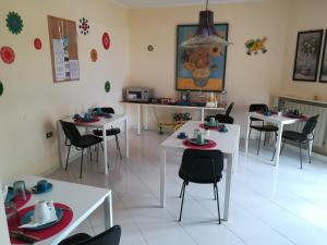 a dining room with white tables and black chairs at b&b le zagare in Caltanissetta