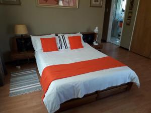 1 dormitorio con 1 cama grande con almohadas de color naranja y blanco en At The View B&B en Roodepoort