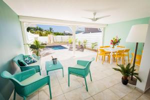 uma sala de estar com mesa e cadeiras e uma piscina em Villa Océan avec piscine privée - Sun Rock ! em Le Diamant