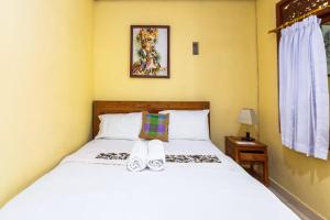 a bedroom with a bed with white sheets at Dekwah Homestay in Ubud