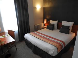 um quarto de hotel com uma cama grande com almofadas em logis le pélican hotel restaurant em Vernantes