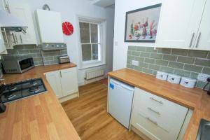 a kitchen with white cabinets and a wooden floor at Norton Apartment by Brighton Holiday Lets in Brighton & Hove