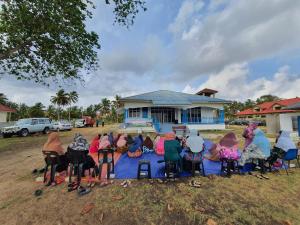 a group of people sitting around a table in front of a house at ALA Beach Lodge - Ketapang Homestay in Kota Bharu