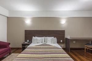 um quarto de hotel com uma cama e um sofá vermelho em Abba Hotel em Betim