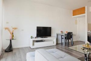 uma sala de estar com um sofá branco e uma televisão de ecrã plano em Gordon beach! 2 bedrooms great location em Tel Aviv