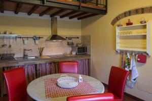 une cuisine avec une table et des chaises rouges ainsi qu'une cuisine avec un comptoir dans l'établissement Agriturismo Casariccio - Casa Margherita, à Bucine