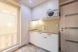 cocina con armarios blancos y microondas en Apartments Bracic Spa, en Sukošan