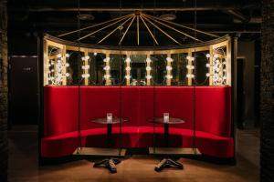 una panchina rossa con due tavoli in una stanza di Ruby Lucy Hotel London a Londra