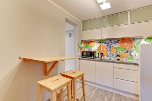 a kitchen with white cabinets and wooden stools at Villa Arkodes in Gdańsk