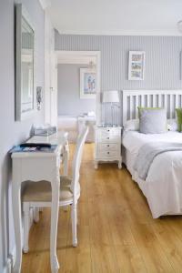 The Cambridge Guest House by Tas في كامبريدج: غرفة نوم بيضاء مع مكتب وسرير