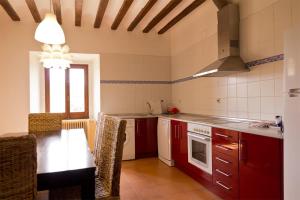 AlmarzaにあるCasa rural Casa Fuerte San Gregorio Iのキッチン(赤いキャビネット、テーブル、椅子付)