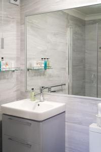 Baño blanco con lavabo y espejo en The Cambridge Guest House by Tas en Cambridge